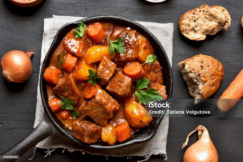 Goulash, beef stew Goulash, beef stew in cast iron pan, top view, close up Stew Stock Photo