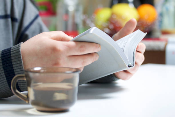 istock A young man reads the Bible with a silver slice sitting at the table. A mug with water is next to it. 945200020