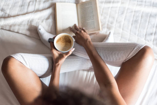 istock black woman reading a book and drinking coffee on bed with socks 945200206