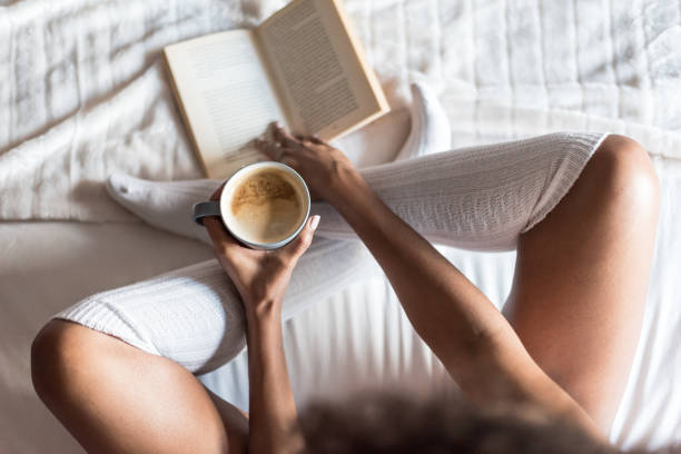 istock woman reading a book and drinking coffee on bed with socks 945200212