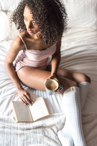 istock woman reading a book and drinking coffee on bed with socks 945200224