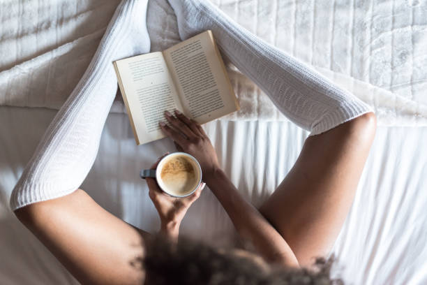 istock woman reading a book and drinking coffee on bed with socks 945200252