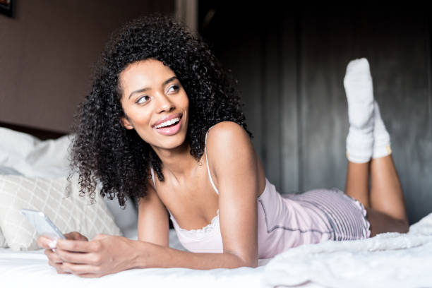 istock woman with her mobile phone on bed 945200360