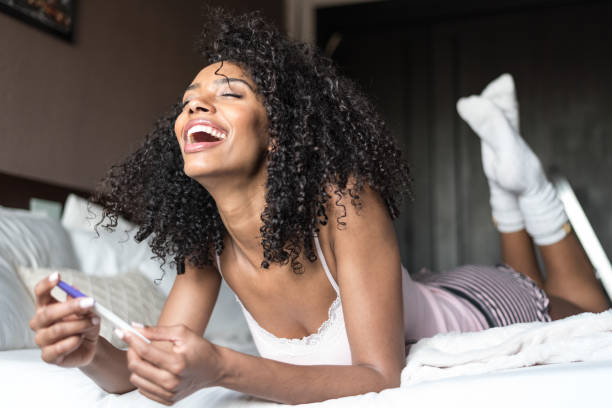 istock happy black woman with a pregnancy test on bed 945200406