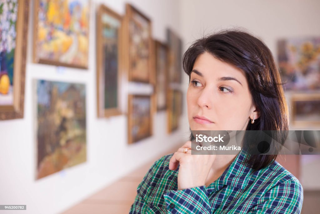 Young woman looking at painting. Young woman looking at painting in art gallery. Critic Stock Photo