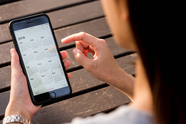 Hand of woman hold iphone 8 plus show calendar of 2018 on screen stock photo