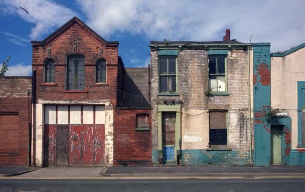 derelict houses and abandoned commercial property on a residential street with boarded up windows and decaying crumbling walls - poor area imagens e fotografias de stock