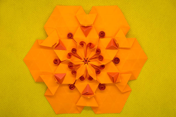 istock Paper quilling and origami composition. Creative orange hexagon isolated on yellow background 945218972
