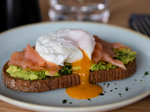 Rye Bread with smashed avocado, smoked salmon and poached egg with yolk flow