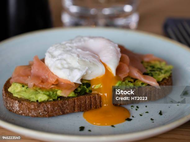 Bread With Avocado Smoked Salmon And Poached Egg Yolk Flowing Stock Photo - Download Image Now