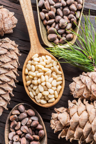 istock Pine nuts in the spoon and pine nut cone on the wooden table. 945227224