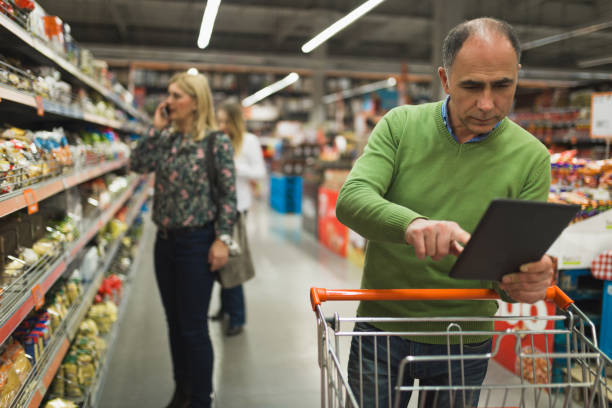 istock Mature man shopping in the supermarket and using digital tablet 945229934