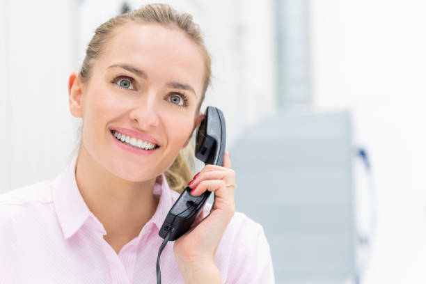 Horizontal color portrait of pretty woman using a telephone an having business discussion at factory warehouse office.