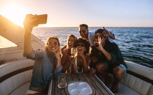 Cheerful young people posing for a selfie at boat party. Crazy friends enjoying a party on private yacht and taking selfie.