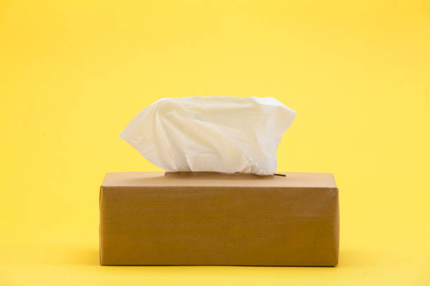 istock Paper tissues in brown box on yellow background 945259756