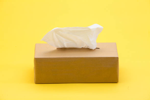 istock Paper tissues in brown box on yellow background 945259786