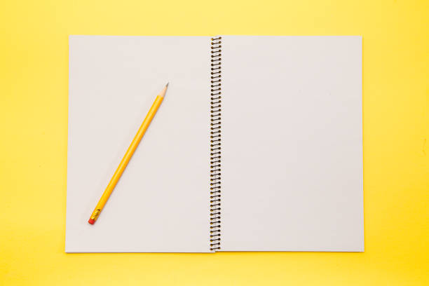 istock Open note book blank pages with yellow pencil on yellow background 945263510