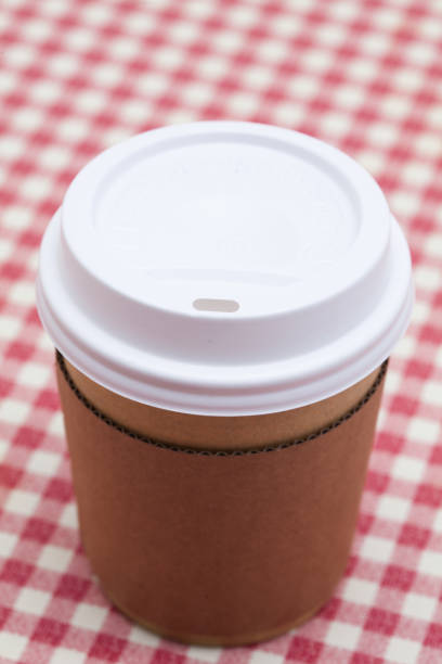 istock Cardboard throwaway coffee cup on red and white checkered table 945264454