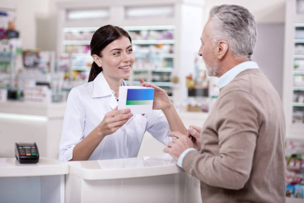 istock Merry female pharmacist assisting senior man 945270882