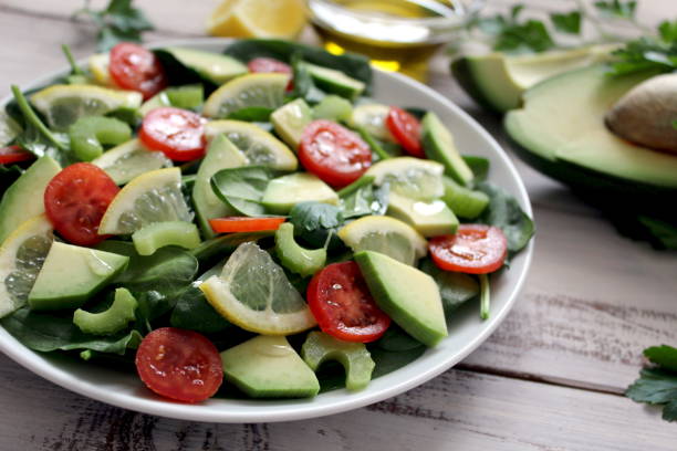istock Avocado salad with vegetables on a wooden background. 945282920