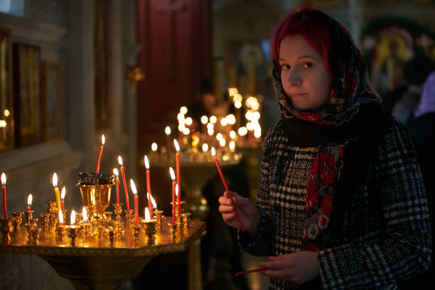 istock Praying young woman with candle 945289020