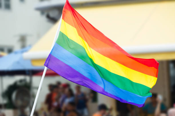 Gay Pride Rainbow Flag Waving on the Street Rainbow flag waving on the street during a gay pride celebration with unrecognizable people lining the sidewalk in the background gay pride parade photos stock pictures, royalty-free photos & images