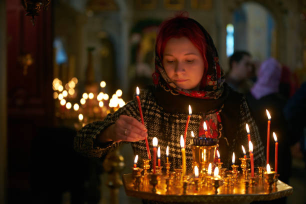 istock Praying young woman with candle 945289234