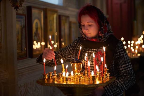 istock Praying young woman with candle 945290014