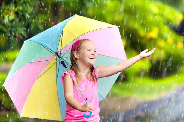 istock Kid with umbrella playing in summer rain. 945290306