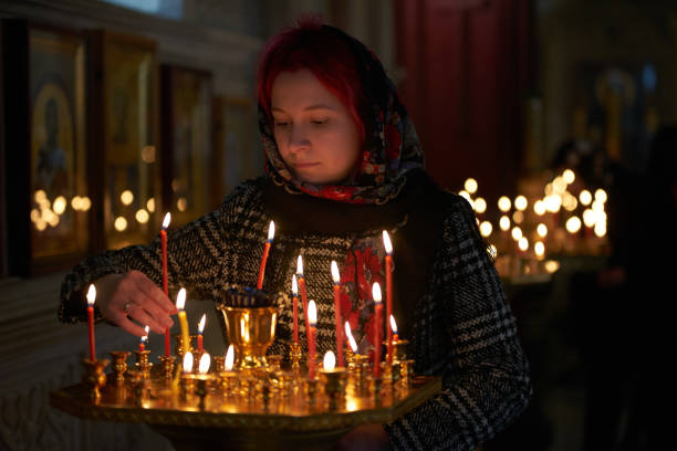 istock Praying young woman with candle 945290490