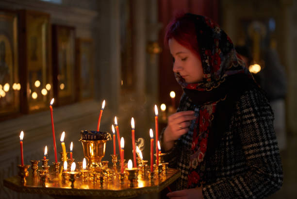 istock Praying young woman with candle 945291046