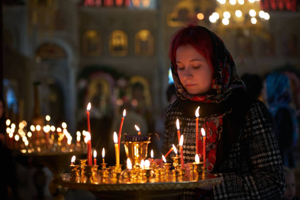 istock Praying young woman with candle 945291350