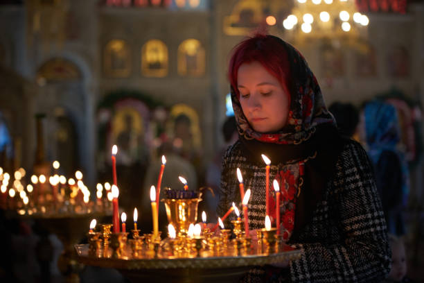 istock Praying young woman with candle 945295842