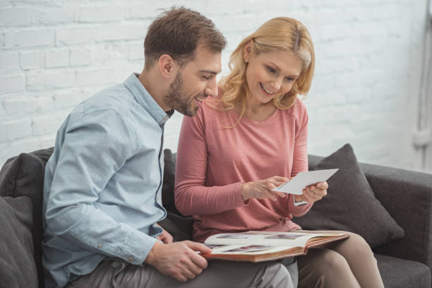 istock mother and grown son looking at photo in hand while resting on sofa together 945296460