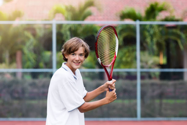 enfant jouant au tennis sur cour extérieure - tennis child teenager childhood photos et images de collection