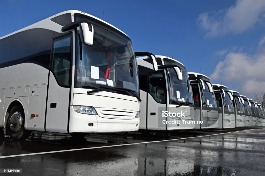 White tourist buses in a row Front right side shot on the white tourist buses in a row on the parking. Bus Stock Photo