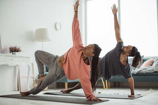 Couple doing yoga at their living room