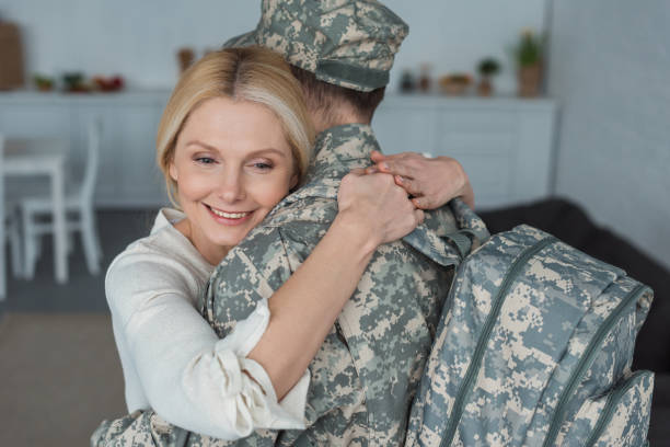 istock smiling mother hugging grown son in military uniform at home 945305516