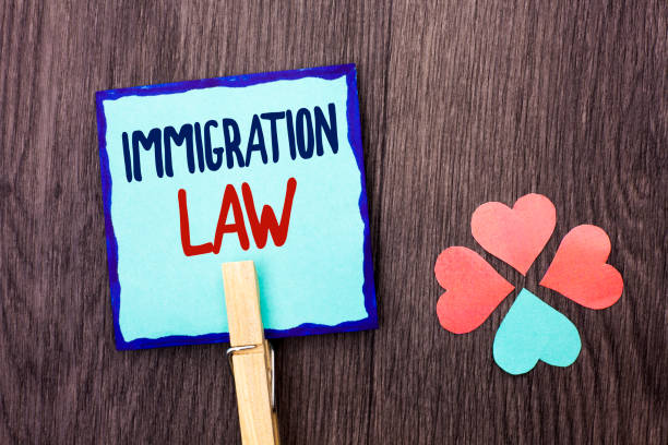 istock Handwriting text writing Immigration Law. Concept meaning National Regulations for immigrants Deportation rules written on Sticky Note Paper Holding With Clip on the wooden background Hearts. 945340570