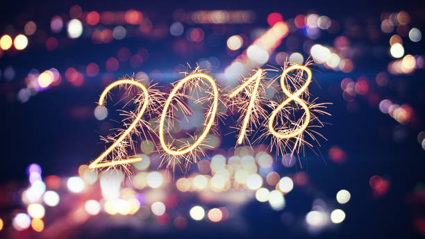 istock 2018 new year sparkler text and city bokeh lights 945343728