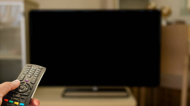 istock person watching television with control and black blank screen 945343848