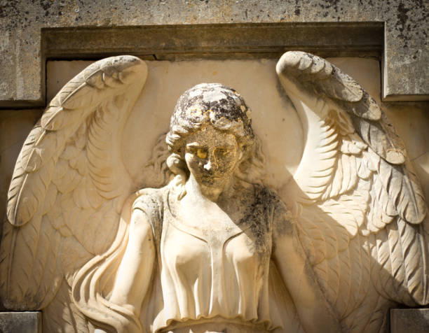 Two Angel statues at dark blue lightened tombstones during dawn in Cementerio General in Merida, Mexico