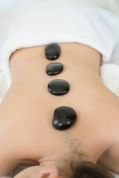 Young beautiful woman getting hot stone spa treatment.\