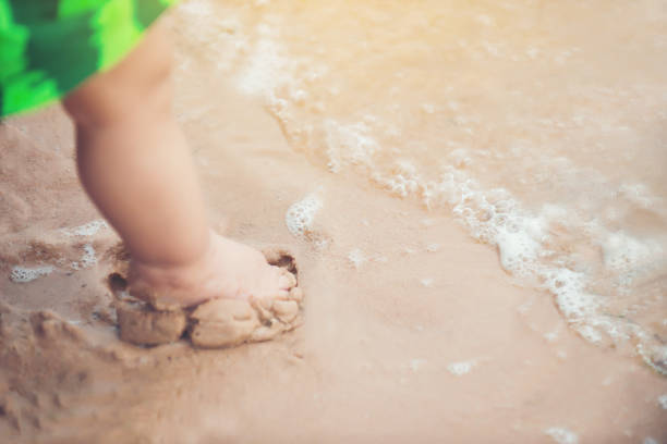 Legs of boy stand on the beach