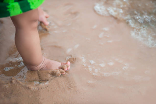 istock Legs of boy stand on the beach 945377836