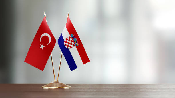 istock Turkish And Croatian Flag Pair On A Desk Over Defocused Background 945381338