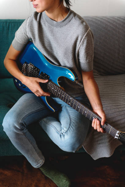 istock Woman playing guitar on a sofa 945383992