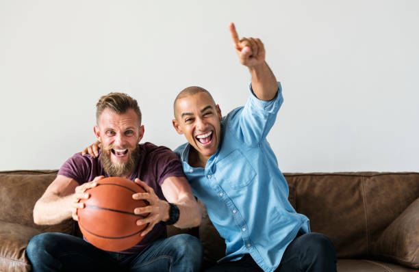 istock Man sitting together on a couch watching sport 945384220