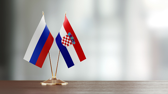 Russian and Croatian flag pair on desk over defocused background. Horizontal composition with copy space and selective focus. American and Croatian flag pair on desk over defocused background. Horizontal composition with copy space and selective focus.