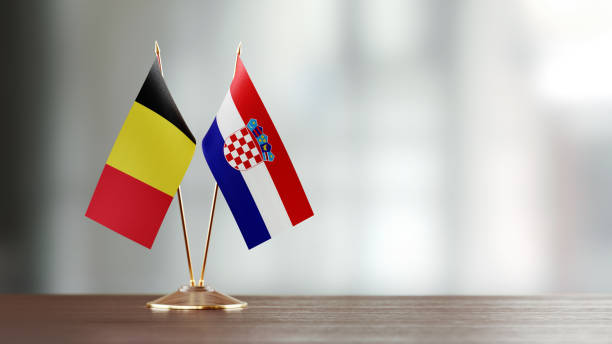 istock Belgian And Croatian Flag Pair On A Desk Over Defocused Background 945387924